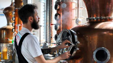 Distiller Sam Garbutt checks distillery controls in the