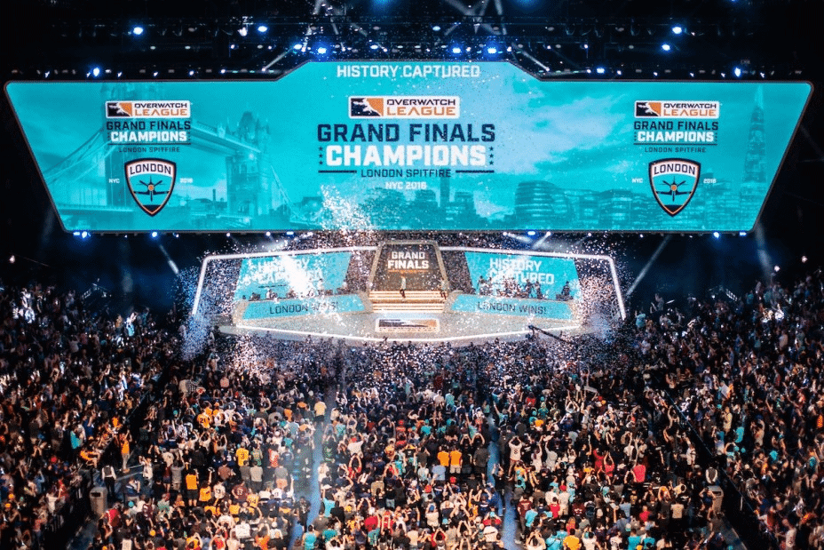A shot of the crowd at the inaugural OWL championships displaying a banner which reads "Grand Final Champions, London Spitfire"