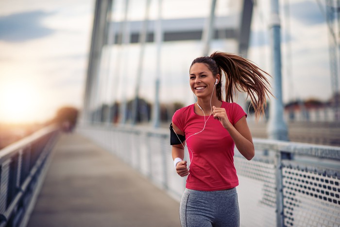A woman listens to music on her smartphone while jogging.
