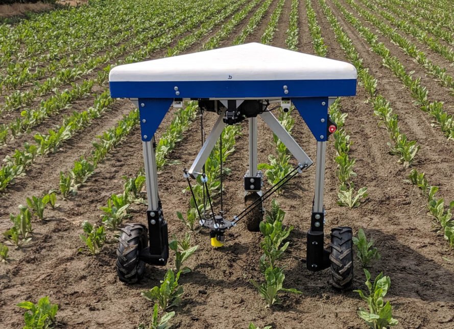 a platform held up by three legs with wheels (the Odd.Bot), out in a green field