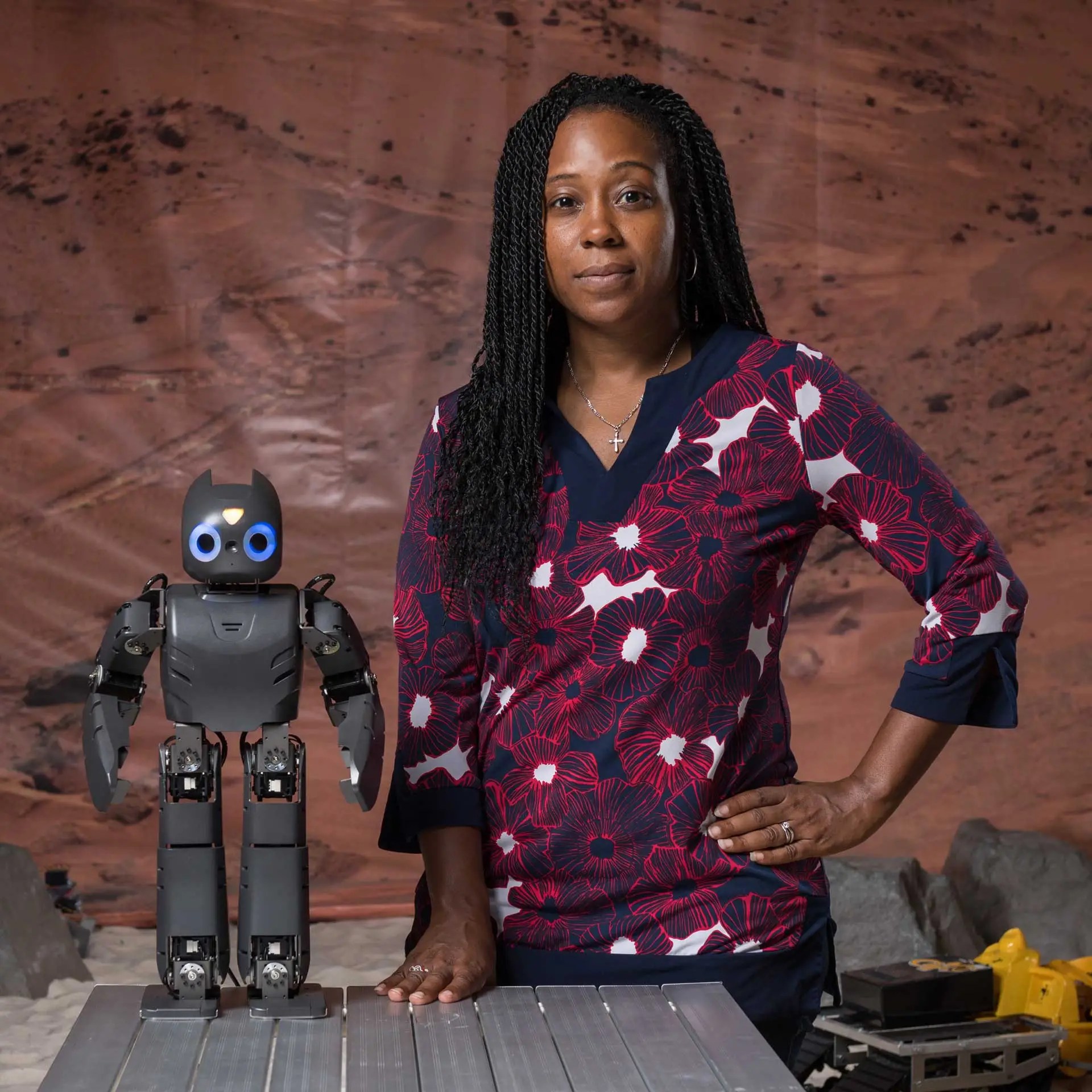 A headshot of roboticist Ayanna Howard standing next to a robot.