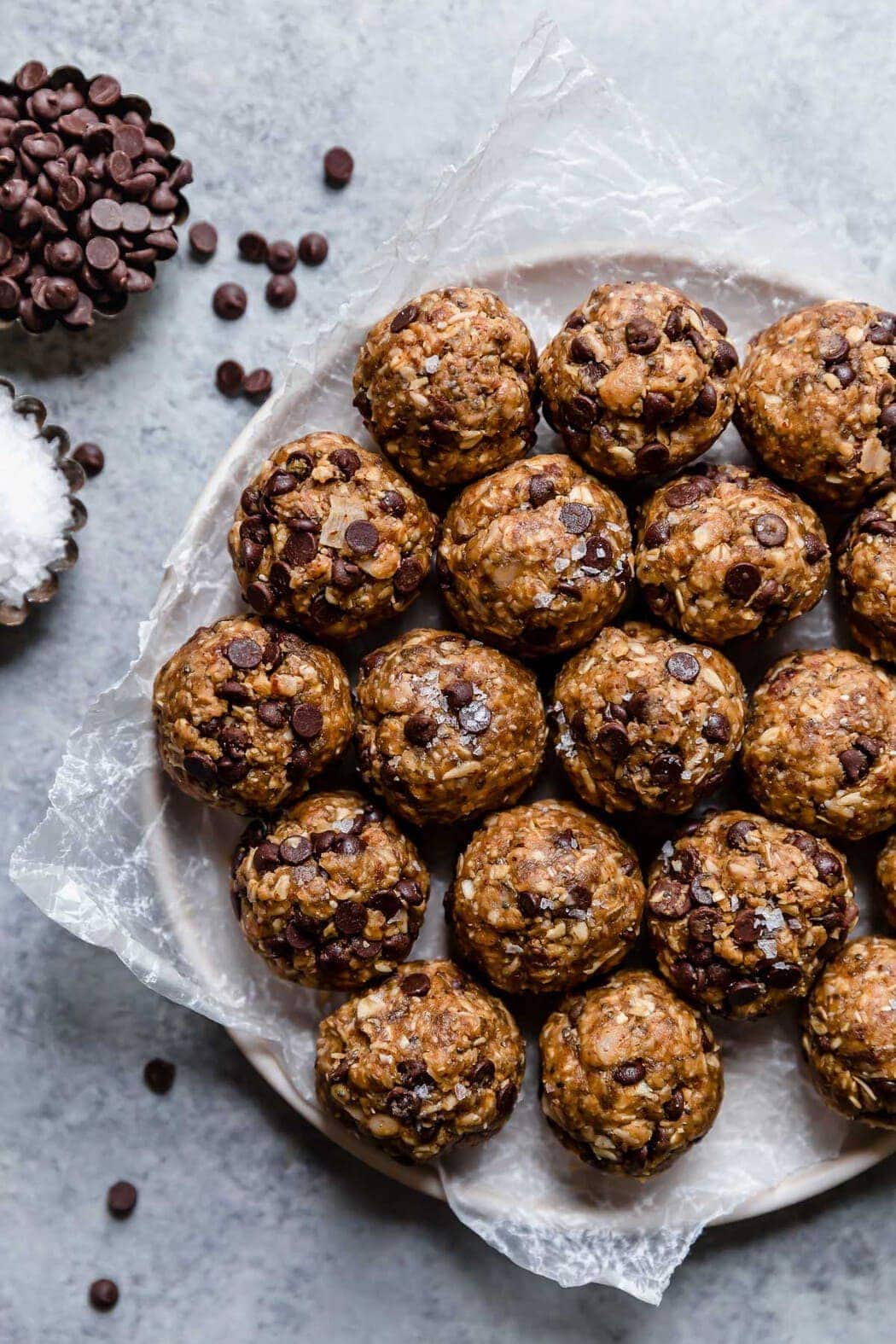 Plate filled with peanut butter chocolate chip energy balls with chocolate chips and coarse salt on the side