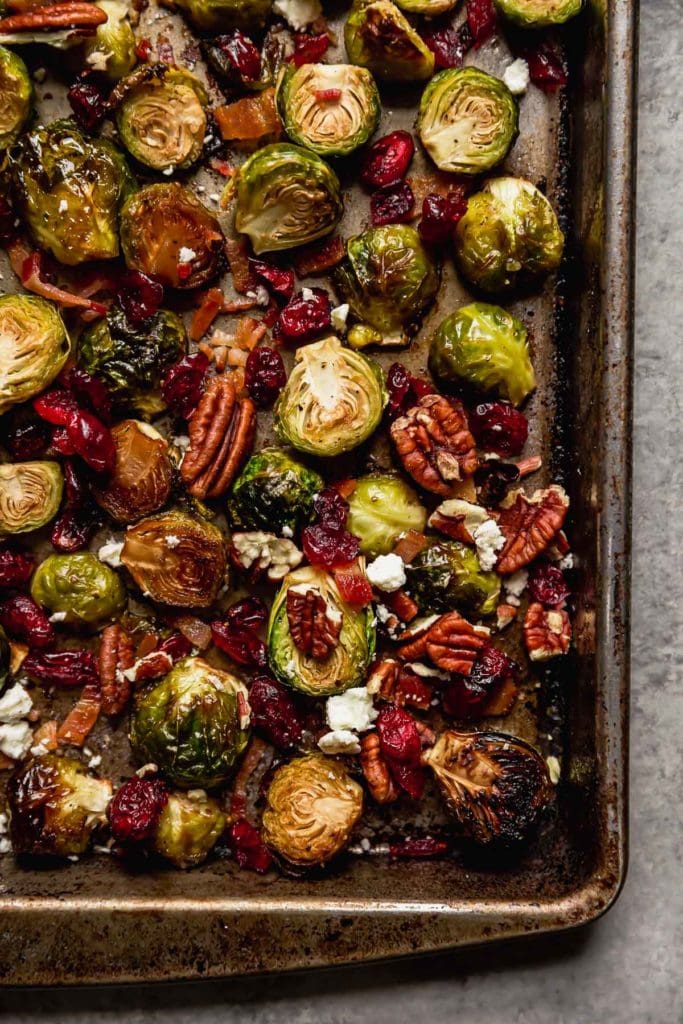 Roasted Brussels Sprouts with Bacon, cranberries, pecans and feta cheese on a pan.